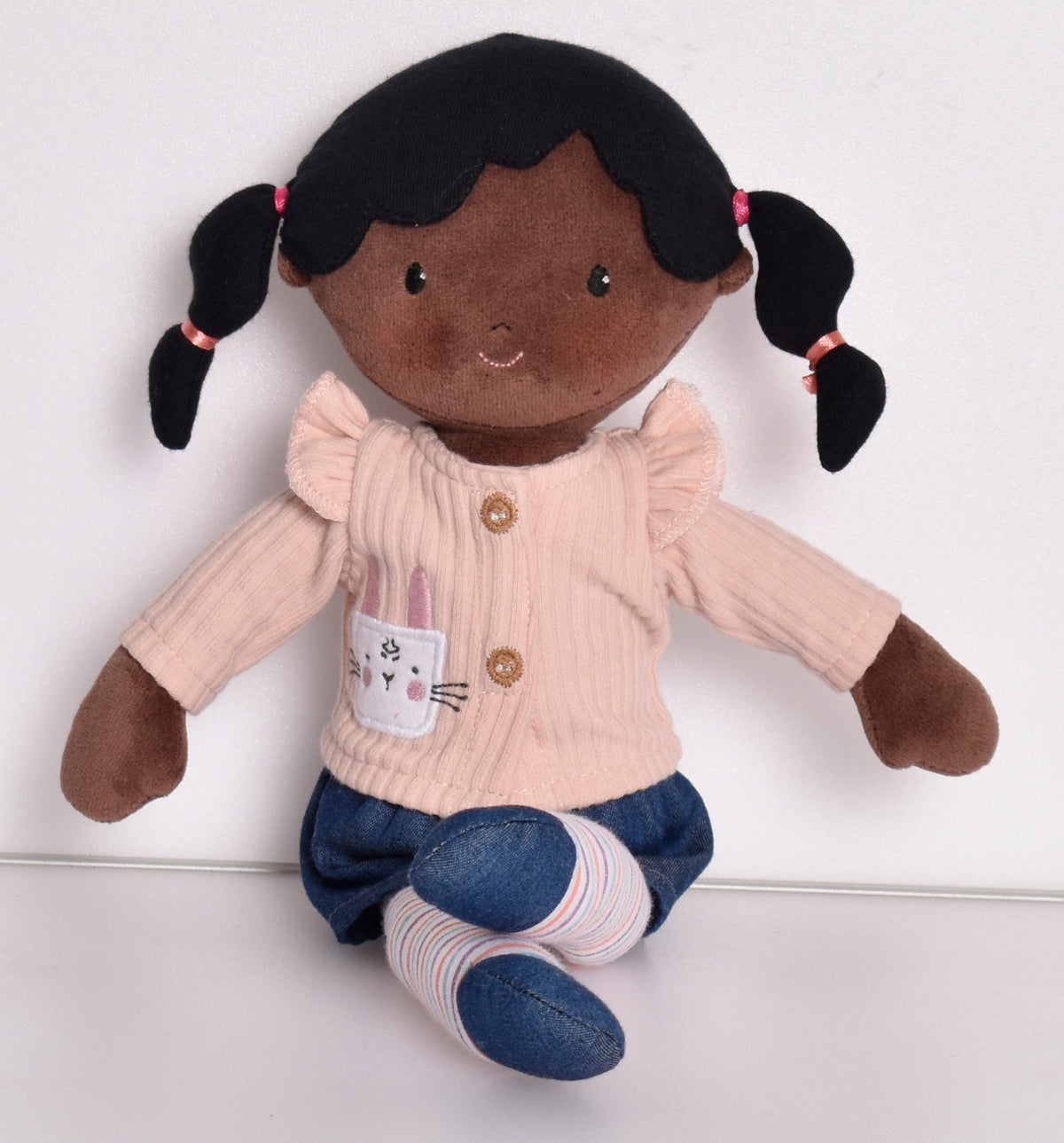 Poupée aux cheveux noirs en pull rose et leggings rayés