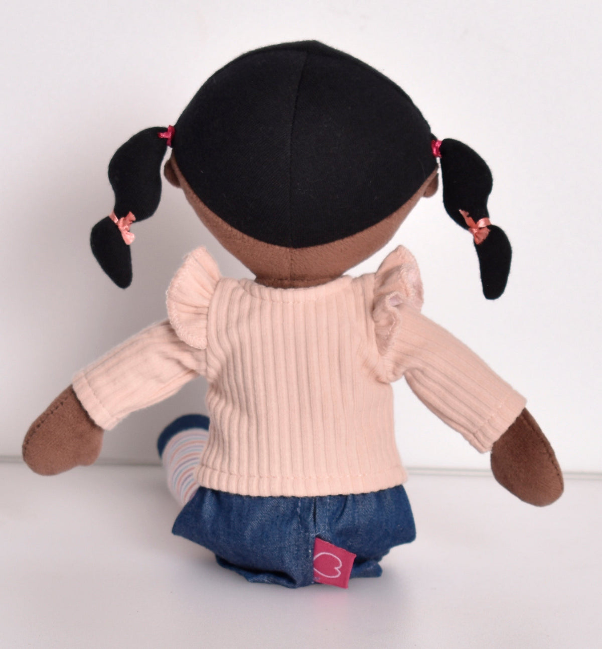 Poupée aux cheveux noirs en pull rose et leggings rayés